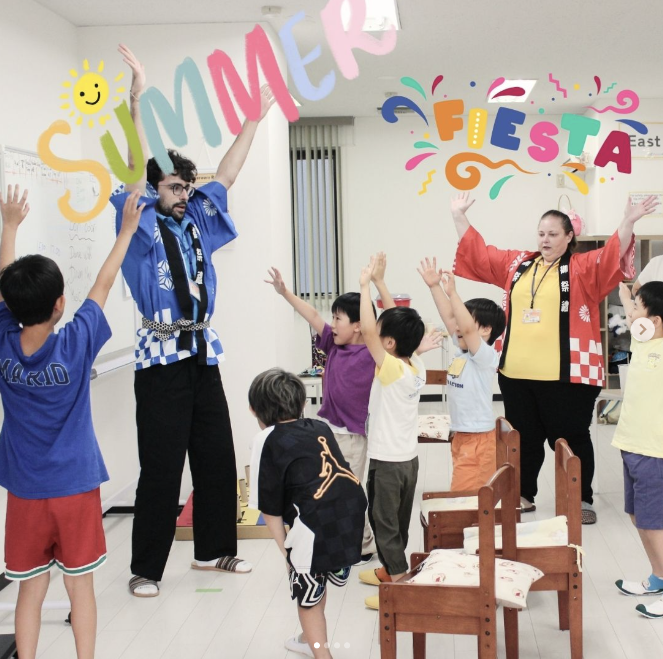 先生と一緒に英語の歌に合わせて笑顔で踊る子どもたち